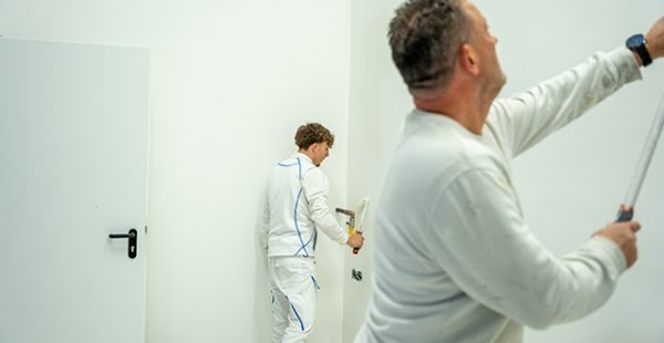 Maler streicht weiße Innenwand mit Farbrolle – Maler Quantius Wandarbeiten